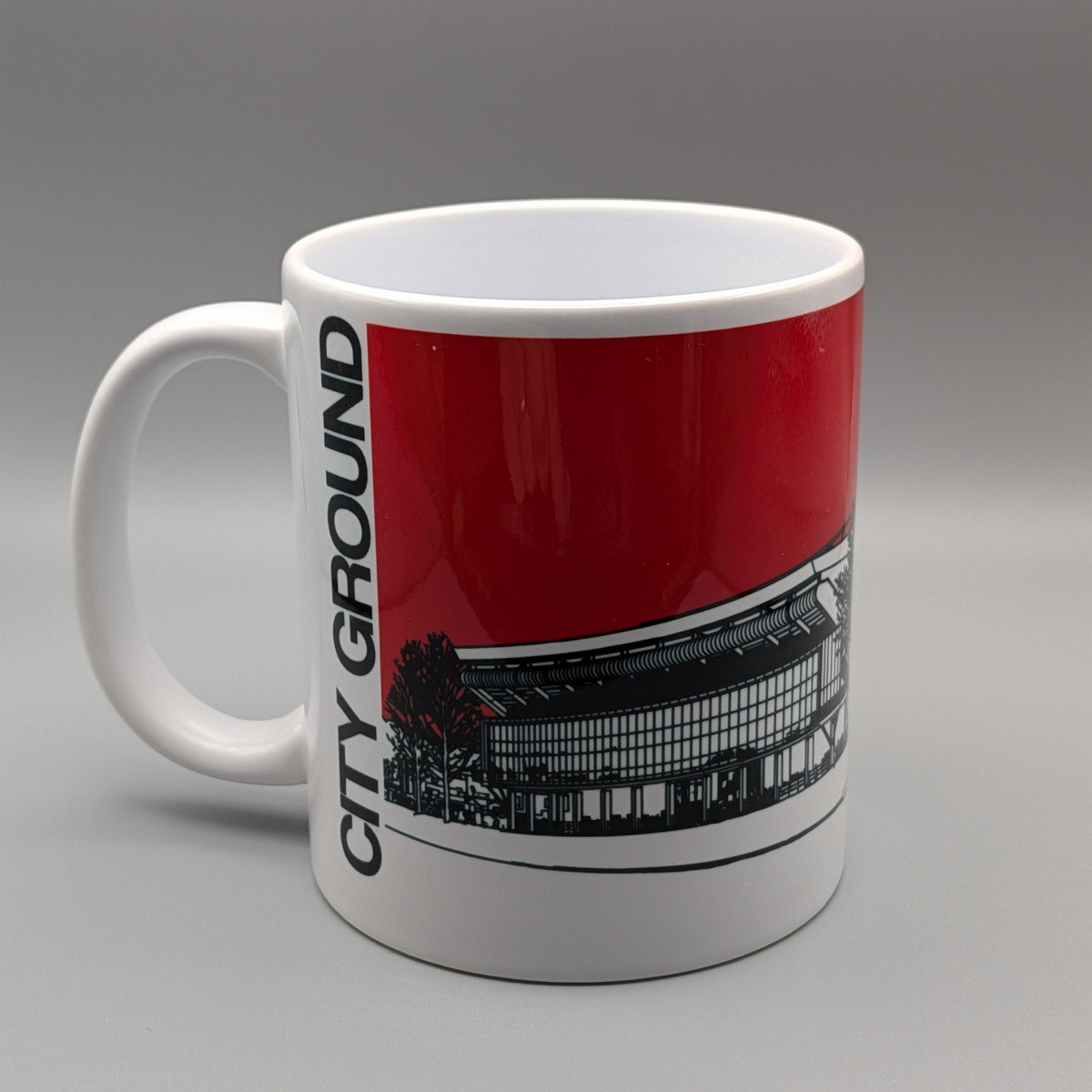 A white ceramic mug featuring a red and black graphic print of the City Ground stadium, with 'CITY GROUND' printed vertically in black on the side.