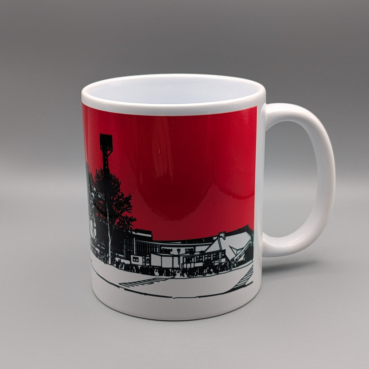 A white ceramic mug with a printed graphic of a street scene under a solid red sky, shown on a neutral gray background.