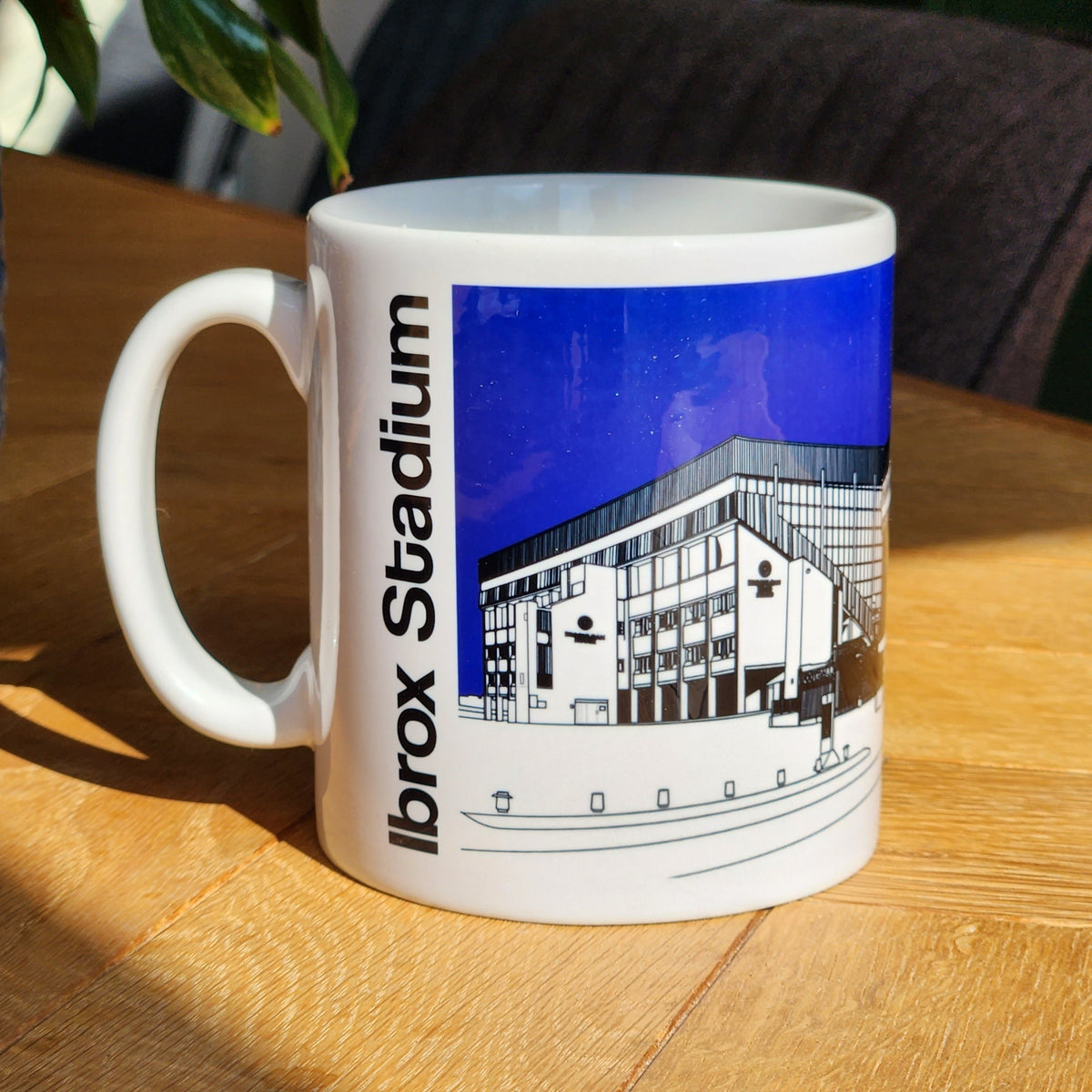 A white ceramic mug with an illustrated design of Ibrox Stadium, the home ground of Glasgow Rangers FC, with the text 'IBROX STADIUM' and the club's crest.